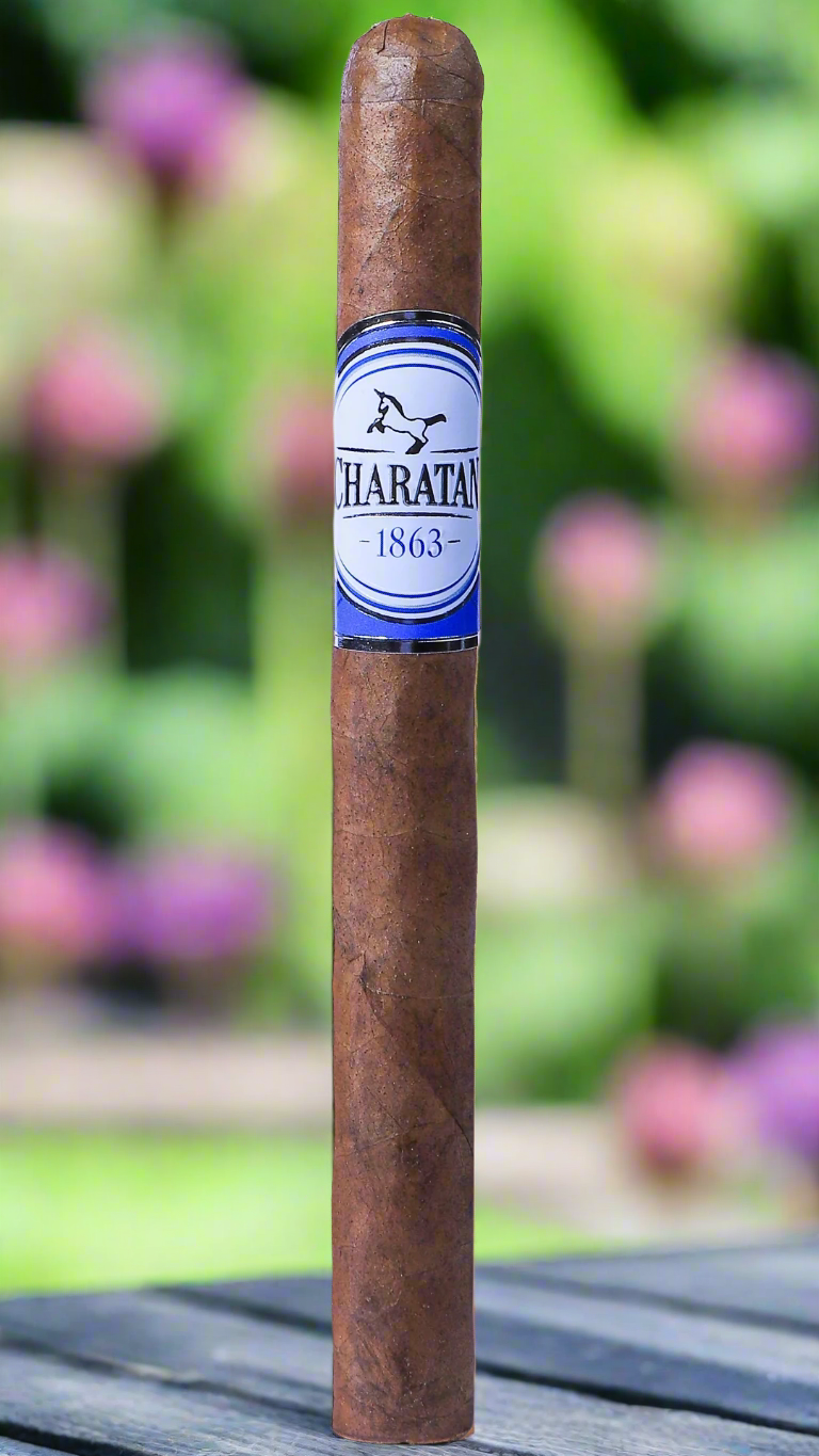 A single Charatan panetela cigar in a garden in summertime.