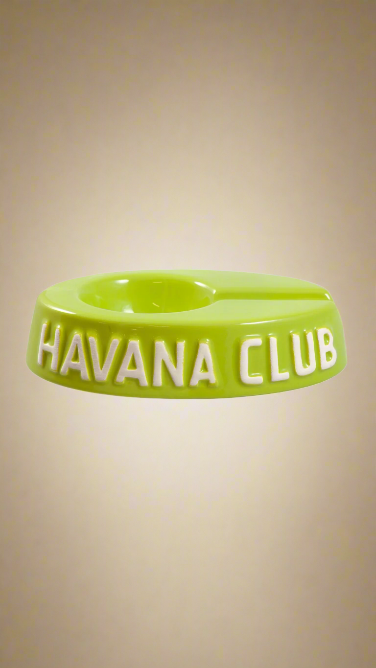 A oval shaped light green glazed ceramic ashtray with a cigar holder on one of the long ends. The words Havana club are embossed on the side, the lettering is unglazed.