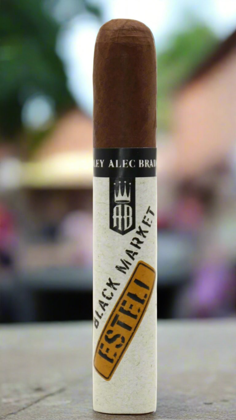 A single Alec Bradley black market punk Esteli cigar against a pub garden background.