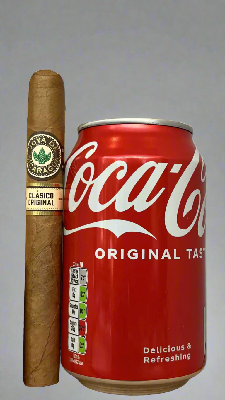 A single Joya De Nicaragua Clasico Seleccion B cigar next to a can of coca cola to show scale, the cigar is a few centimetres longer than the can.