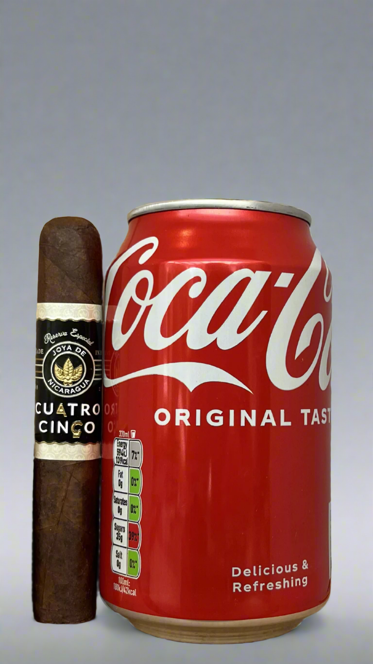 A single Joya De Nicaragua Cuatro Cinco Petit Corona cigar next to a can of coca cola to show scale, the cigar is the same length as the can.