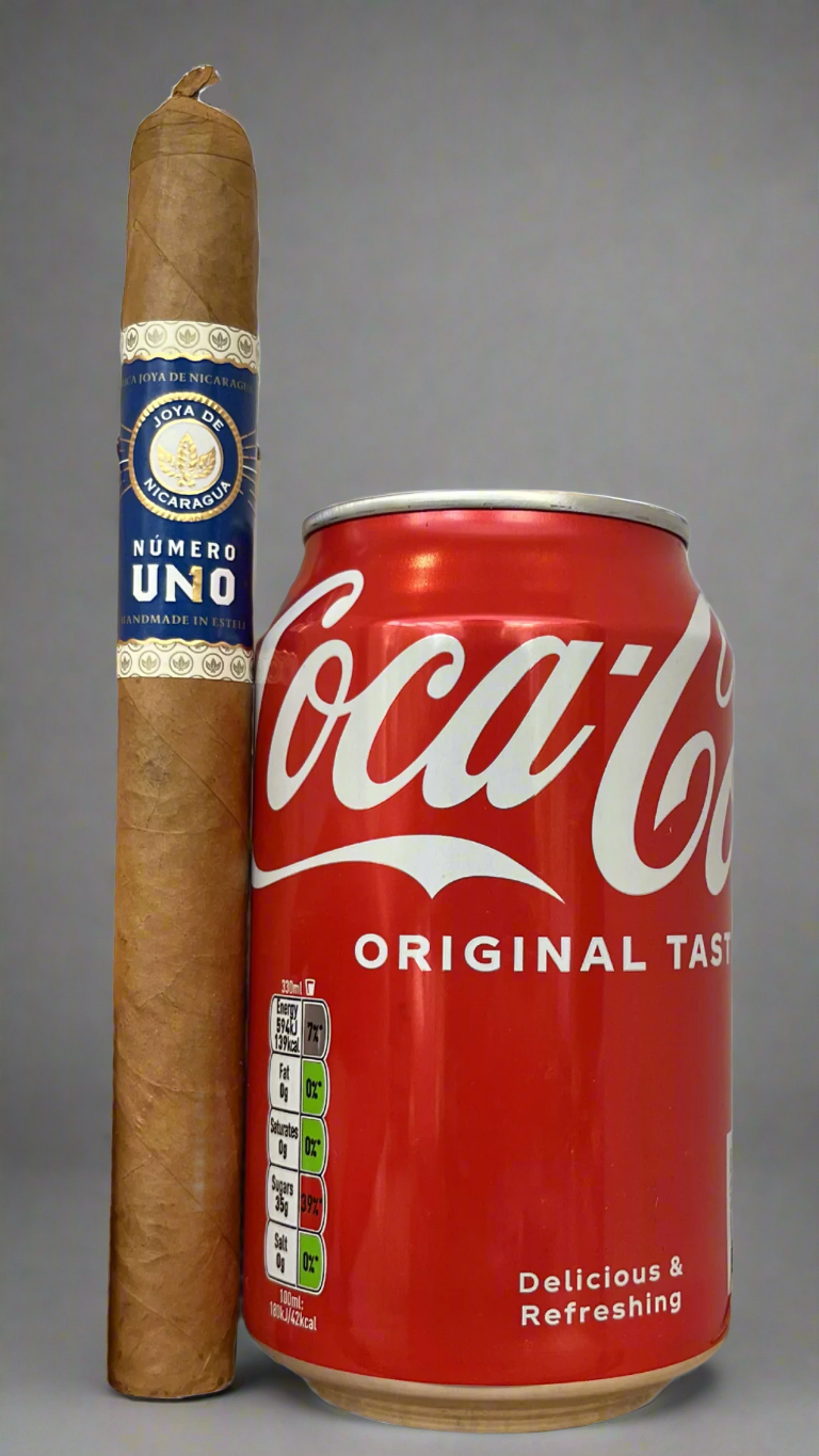 A single Joya De Nicaragua Numero Uno L'ambassadeur cigar next to a can of coca cola to show scale, the cigar is about 50% bigger than the can.