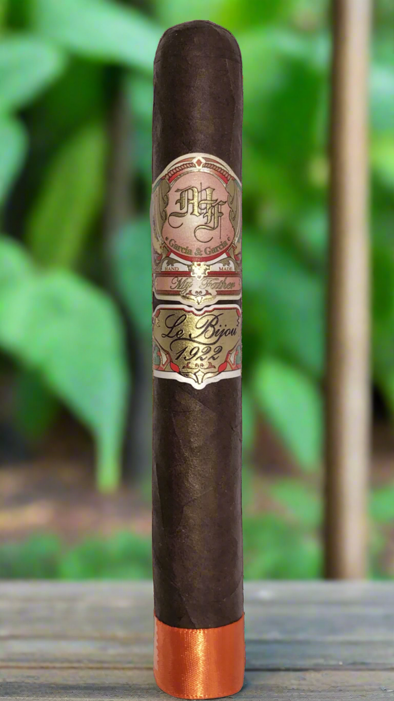 A single My Father Le Bijou 1922 Toro on the porch of a house overlooking a tobacco field.