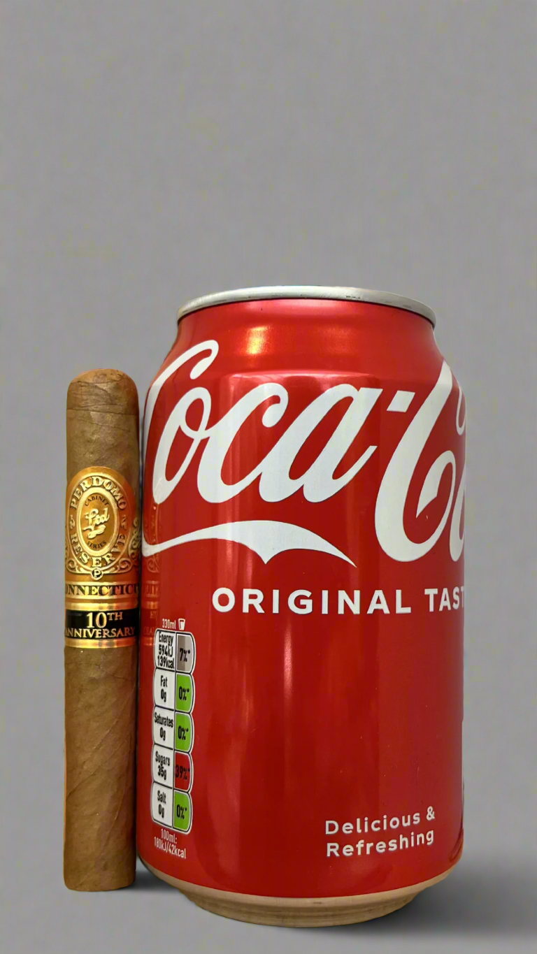 A single Perdomo 10th Anniversary Connecticut Petit Corona Cigar next to a can of coca cola to show scale, the cigar is a few centimetres shorter than the cigar.