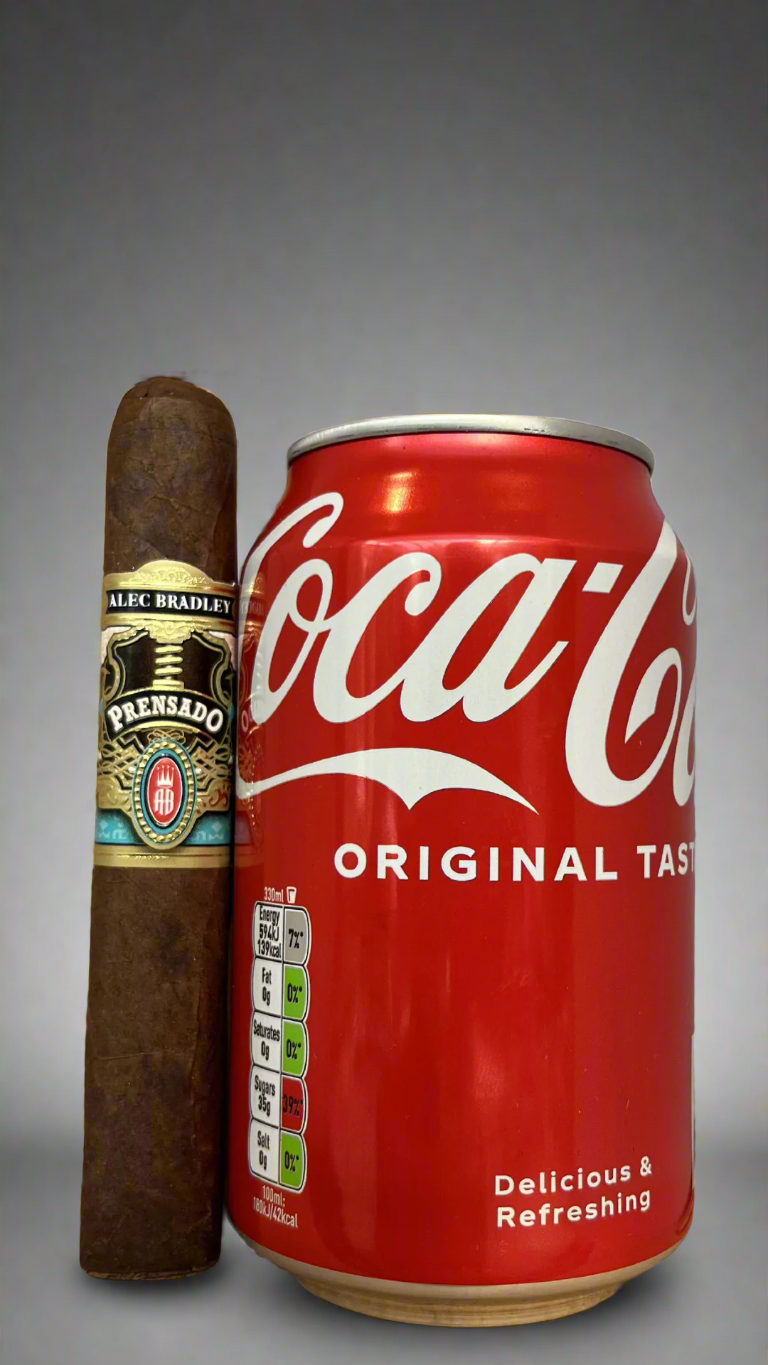 A single Alec Bradley Prensado Corona Gorda cigar next to a can of coca cola, the cigar is slightly longer than the can.