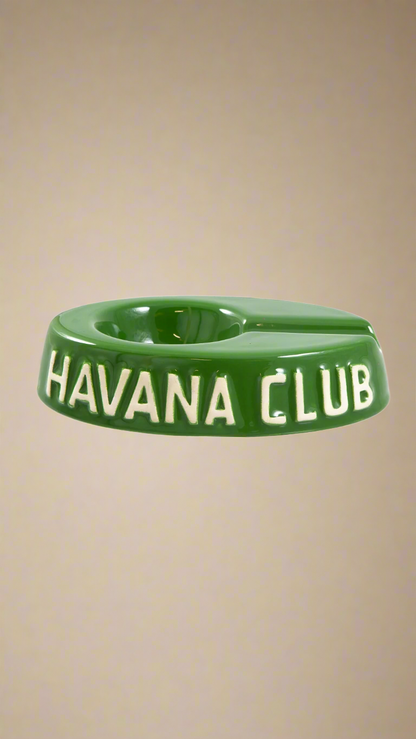 A oval shaped green glazed ceramic ashtray with a cigar holder on one of the long ends. The words Havana club are embossed on the side, the lettering is unglazed.